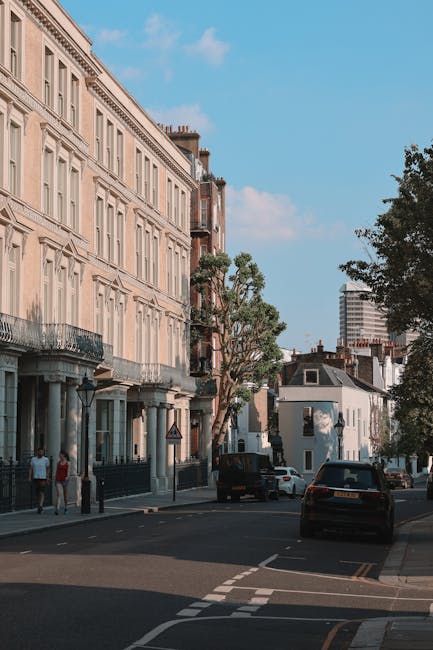 A street scene in Fulham showing a typical residential neighbourhood with white-painted terraced houses on both sides, each featuring black iron balcony railings and windows with flower boxes. Parked